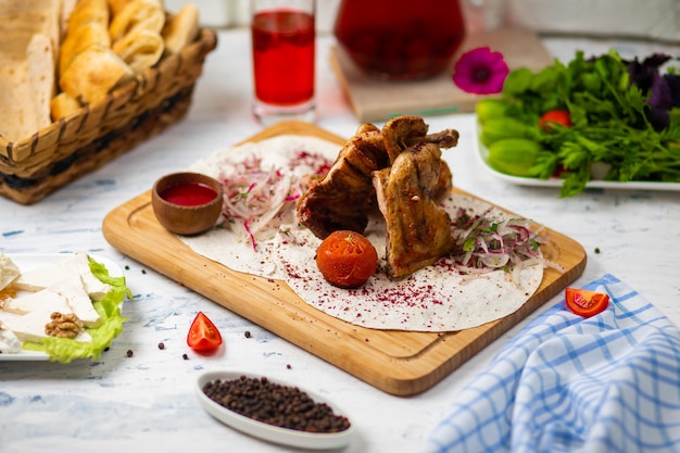 Marinated grilled healthy chicken breasts cooked on a summer BBQ and served in lavash with fresh herbs, wine, bread on a wooden board, close up view 