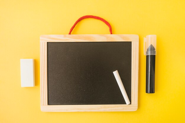 Free photo marker and eraser near blackboard and chalk