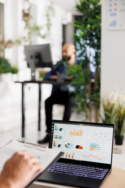 Free photo market research statistics graphs on laptop screen in start up company business office. employee analyzing financial performance chart and metrics on portable computer in coworking space