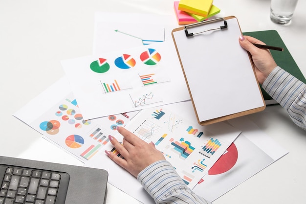 Marketing business lady in striped shirt in office with computer holding notepad with graphs