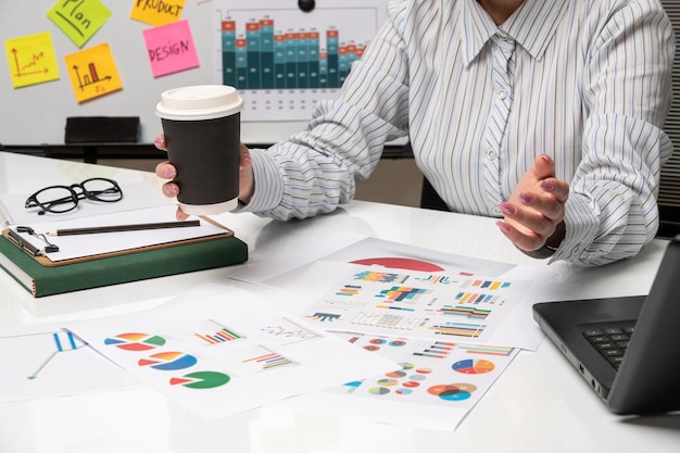 Marketing business lady in striped shirt in office with computer with coffee cup