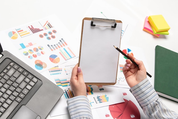 Marketing business lady in striped shirt in office with computer writing in notepad