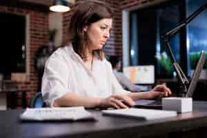 Free photo marketing company businesswoman sitting in office workspace while reviewing accounting documentation. startup project manager using laptop to analyze financial charts and promoting campaign budget.