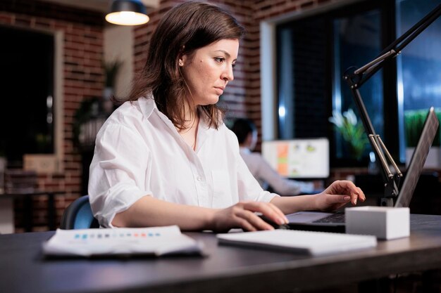 Marketing company businesswoman sitting in office workspace while reviewing accounting documentation. Startup project manager using laptop to analyze financial charts and promoting campaign budget.