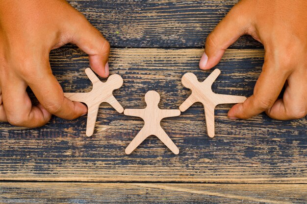 Marketing concept on wooden background flat lay. hands touching wooden figures.