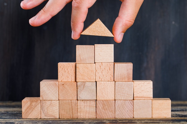 Marketing concept on wooden and dark background side view. hand arranging wooden block as stacking.