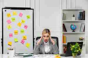 Free photo marketing pretty young blonde girl in grey suit in the office tired and confused