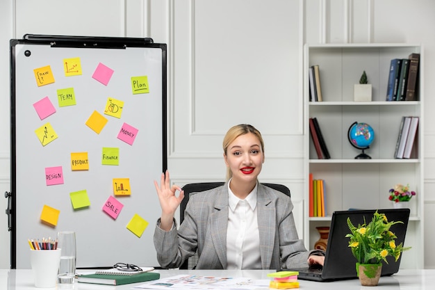 Free photo marketing pretty young blonde girl in grey suit in the office very friendly saying hi