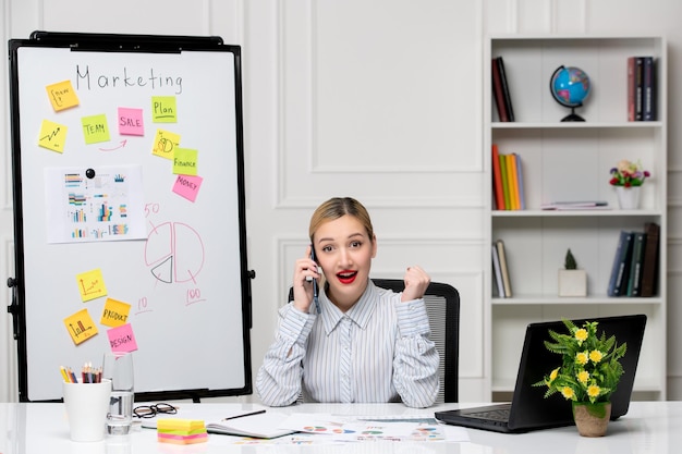 Foto gratuita marketing intelligente signora d'affari carina in camicia a righe in ufficio entusiasta per una conversazione al telefono