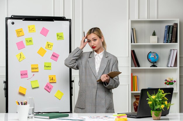 Marketing young pretty cute business lady in grey blazer in office holding temples very focused