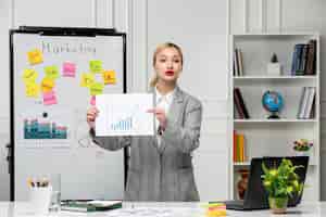 Free photo marketing young pretty cute business lady in grey blazer in office showing statistics to team