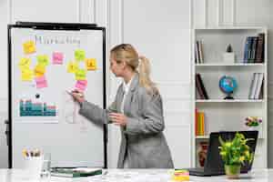 Free photo marketing young pretty cute business lady in grey blazer in office writing new business idea