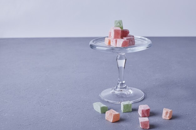 Marmelade candies in a glass cup on blue.