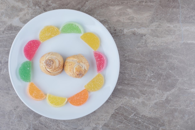 Marmelades around tiny cakes on a platter on marble 