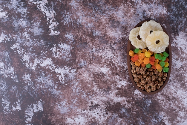 Мармелады и сухие нарезанные фрукты на деревянной тарелке на мраморном столе