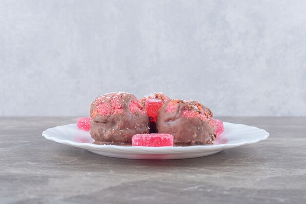 Marmelades and tiny cakes on a platter on marble surface