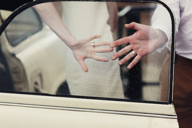 Free photo married couple holds their hands with rings on car's window