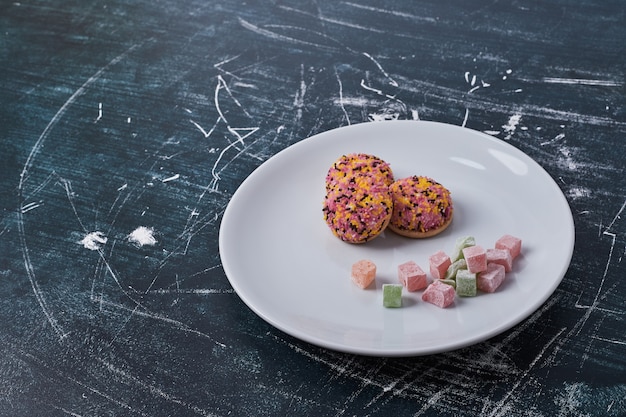 Free photo marshmallow cookies with jelly candies in a white plate.