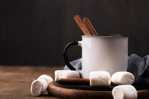 Marshmallow drink with cinnamon on wooden board