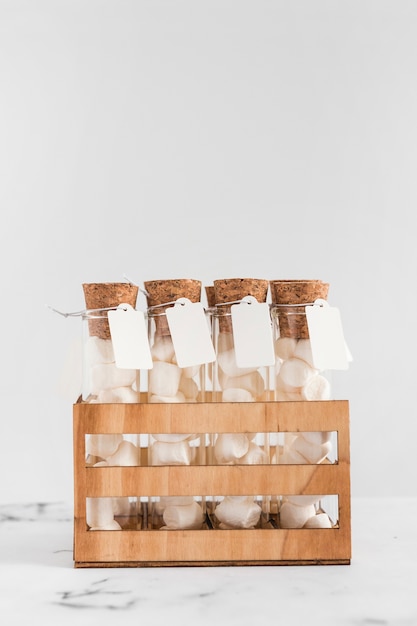 Marshmallow test tubes with tag in crate against white background