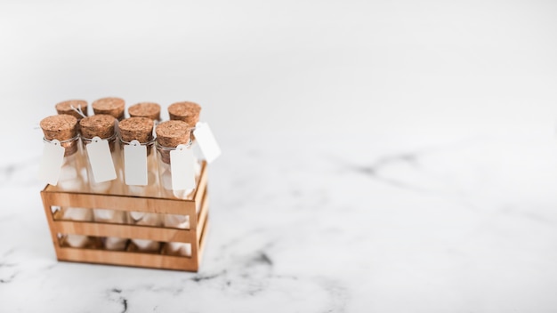 Marshmallow test tubes with tag in crate on marble background