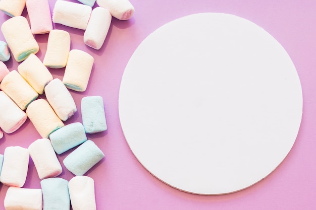 Marshmallows near the blank circular frame on pink backdrop