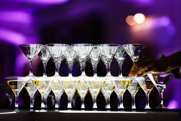 Martini glasses make pyramid on glass table 