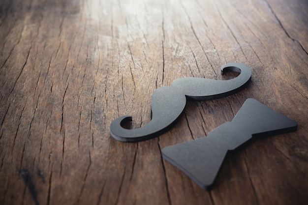 Masculine mustache and black bow placed on the old wooden floor