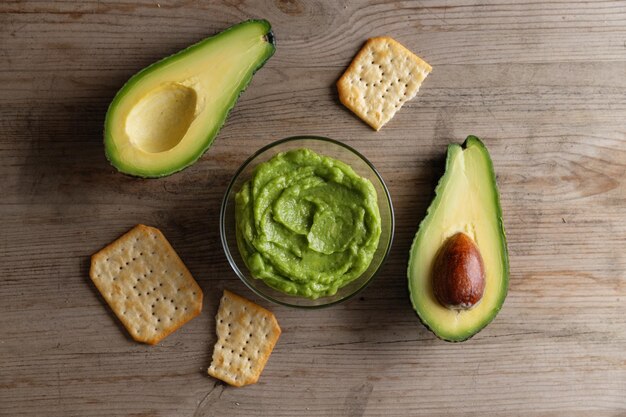 Mashed avocado guacamole sauce in bowl with crackers