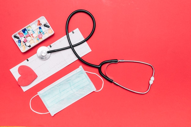 Mask and medicines near stethoscope and cardiogram