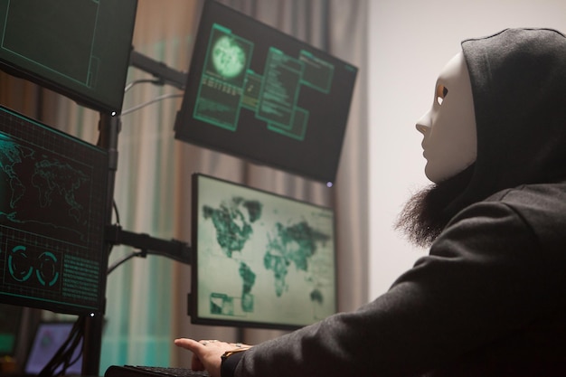 コンピューター​を​使用して​世界中​の​政府​に対する​大​規模​な​サイバー​攻撃​を​計画する​パーカー​を​持った​マスク​された​ハッカー​。