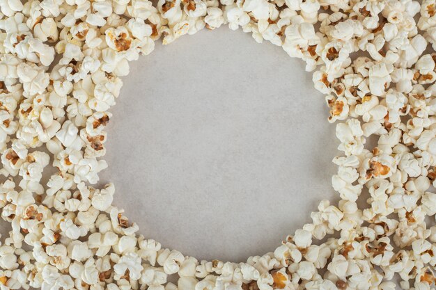 Mass of popcorn with an empty circular space in the middle, on marble.