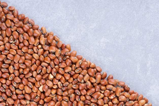 Mass of red beans arranged in a triangular shape on marble surface