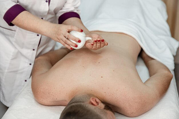 Massage therapist pours oil for massage, relaxing body massage using oils.