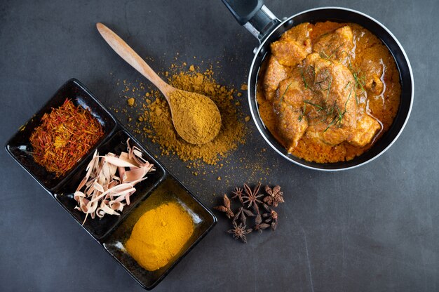 Massaman curry in a frying pan with spices on the cement floor