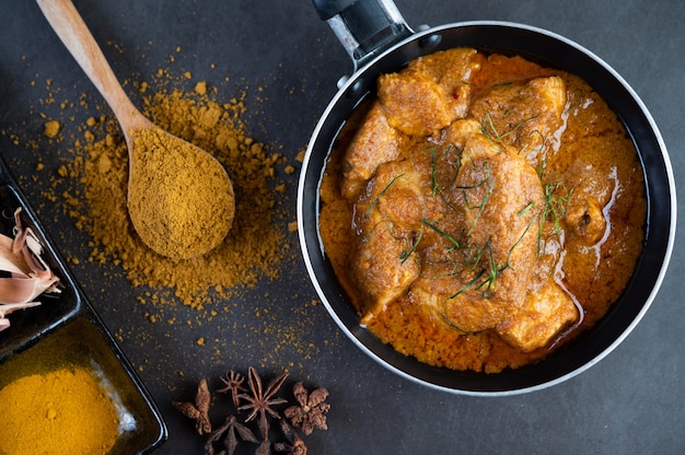 Massaman curry in a frying pan with spices on the cement floor