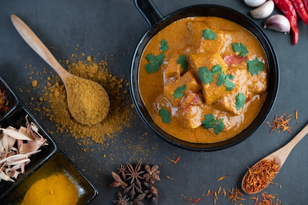 Massaman curry in a frying pan with spices on the cement floor