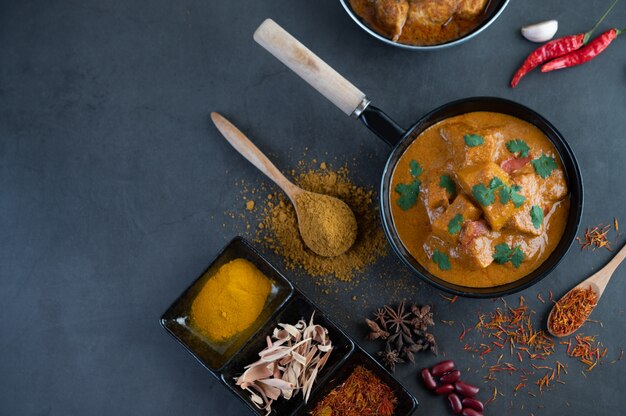 Massaman curry in a frying pan with spices on the cement floor