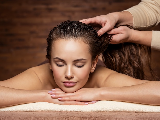 Masseur doing massage the head and hair for an woman in spa salon