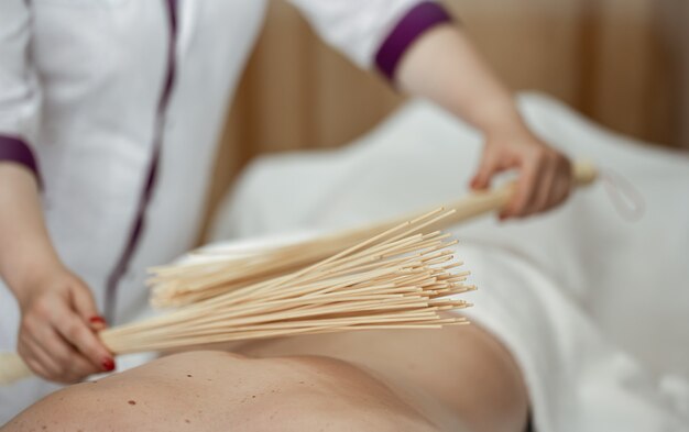 The masseur gives a Japanese massage to a man with bamboo brooms.