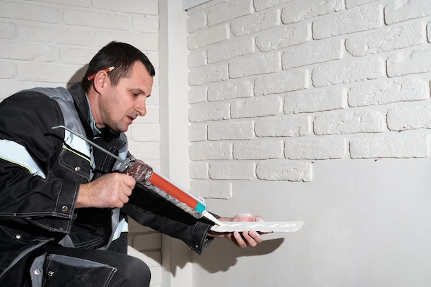 Master applies glue tiles for facing the house The master builder decorates the walls of the apartment Finishing the building with modern materials