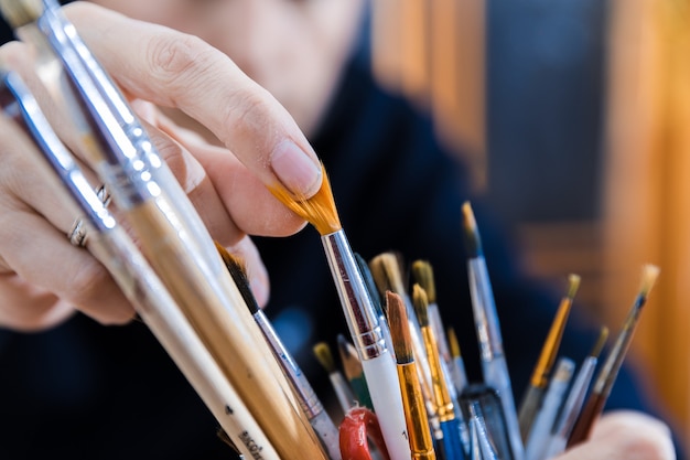 Master choosing painting brush from the stock.