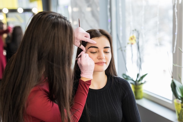 Master doing make-up with wide black eyebrow lines