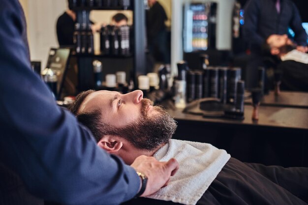 A master hairdresser prepares the face for shaving in the barber shop.