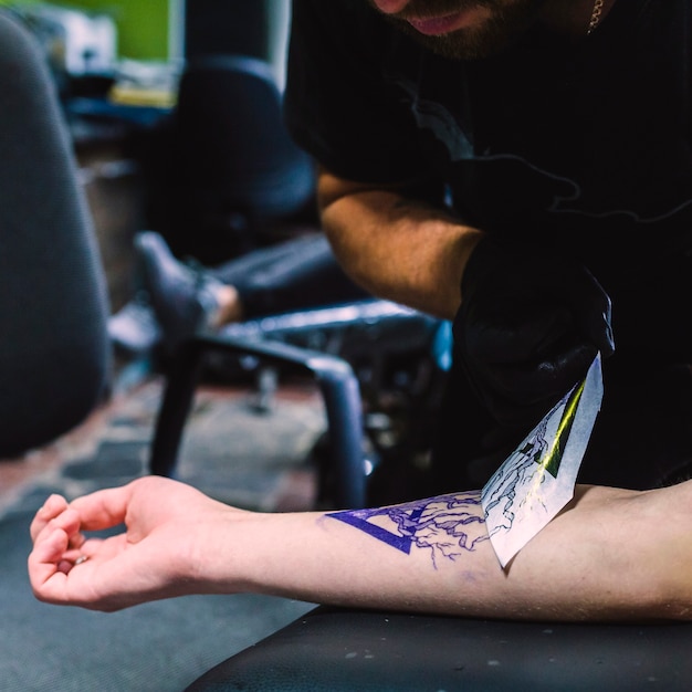 Master making stencil on arm in tattoo studio