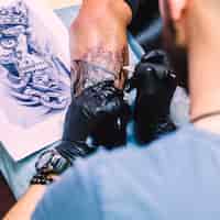 Бесплатное фото Мастер, делающий татуировку с железом