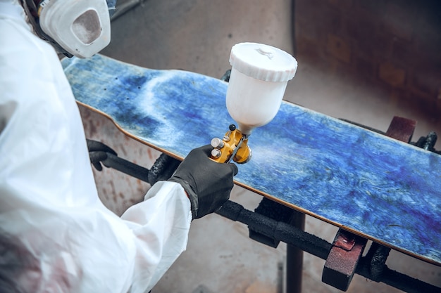 Foto gratuita maestro pittore in una fabbrica - pittura industriale del legno con pistola a spruzzo.