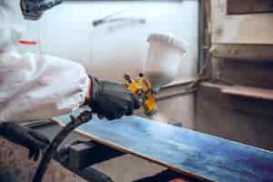 Free photo master painter in a factory - industrial painting wood with spray gun.