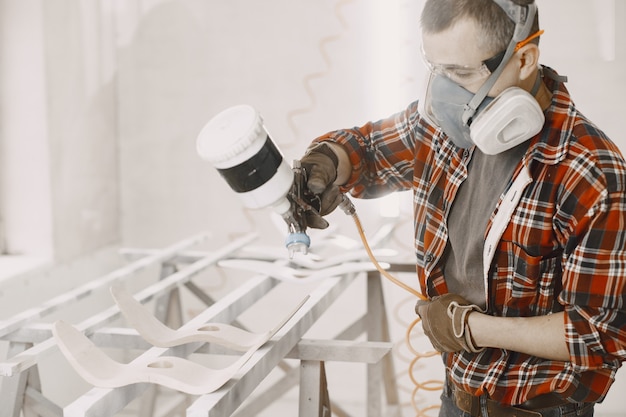 Master painter in a factory painting wood with spray gun