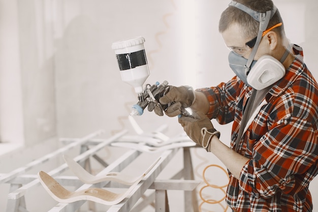 Master painter in a factory painting wood with spray gun